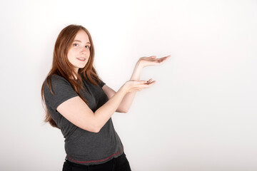 Young red haired woman wearing a grey shirt over isolated white background smiling at the camera while presenting with her hands