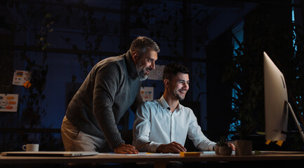 Portrait of two male colleagues working on a joint project long into the night in the office