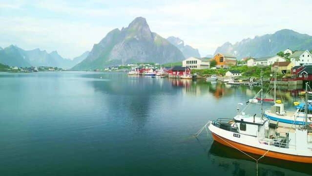 Drone shot of Norwegian traditional fishing boats in Lofoten Island port harbor. scenic fjord village with cabins in Norway. Nordic adventure tourism in summer.