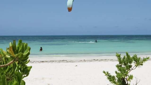 couple watching kite surfer at Jambiani beach in Zanzibar  