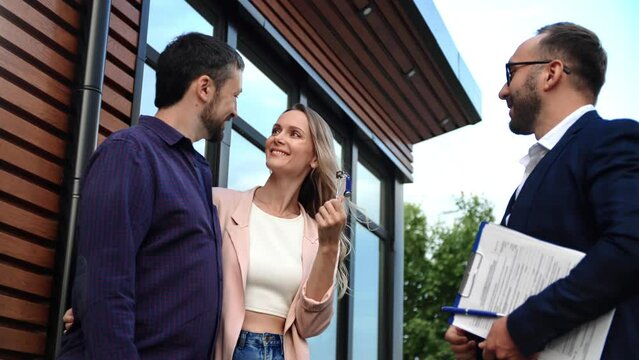 Male real estate agent giving keys happy couple family home owner buying house cottage making deal - Powered by Adobe