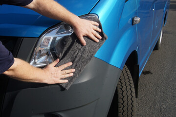Male hands wipe a car headlight with a rag. Cleaning car headlights.