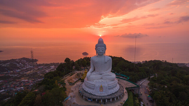 .aerial view stunning pink sky in sweet sunset at Phuket big Buddha. .the sun shines through the clouds impact on ocean surface .The beauty of the statue fits perfectly with the charming nature..