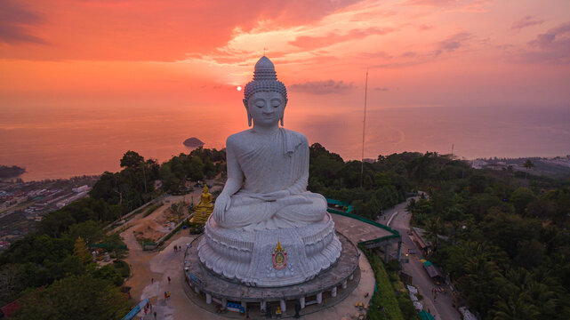 .aerial view stunning pink sky in sweet sunset at Phuket big Buddha. .the sun shines through the clouds impact on ocean surface .The beauty of the statue fits perfectly with the charming nature..
