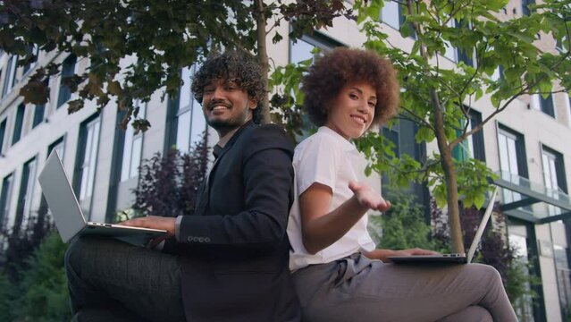 Multiracial business colleagues multiethnic diverse co-workers Indian businessman man African American woman businesswoman in city working with computers laptops invite to coworking welcome come here