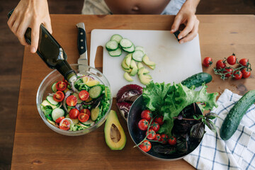 Close-up from above of female hands preparing vegetable salad.