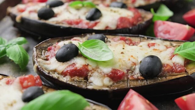 Healthy Eggplant or Aubergine pizza with tomato sauce, mozzarella cheese, basil and olives. Rotating video