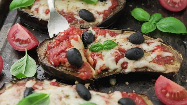 Eating Eggplant or Aubergine pizza with tomato sauce, mozzarella cheese, basil and olives