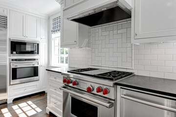 Luxury White Modern Kitchen Interior with White Cabinets with Gas Stove and Black Stone Counters