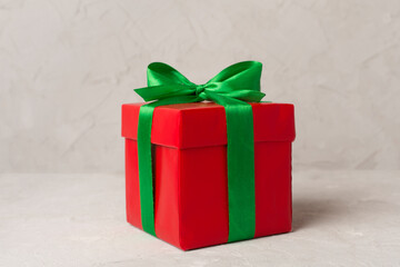 Red gift box with green ribbon and bow on table