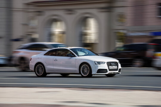 Audi A5 Coupe on the road in motion. Fast speed drive on city road. Front side view of moving white car on the street
