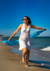 Happy beautiful woman walking on sunny beach
