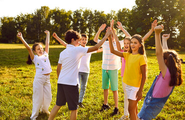 Happy children friends standing together outdoors, having fun and smiling in the park on holidays enjoying spending time in a summer camp. Portrait of a kids having weekend activity.
