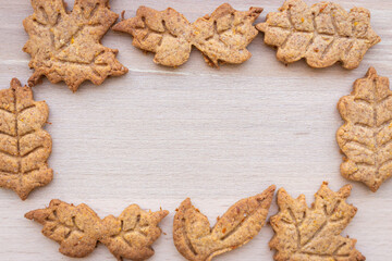 Autumn leaf shaped cookie in frame. Gingerbread pastry with copy space. Autumn festive cookies. Handmade bakery. Gingerbread cookie form. Homemade dessert in sunlight. Autumn mood.