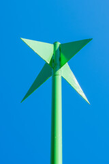 Industrial, complex shape, metal, green construction. Part of sea navigation buoy. Clear, blue sky in the background. Copy space. Background for quotes.