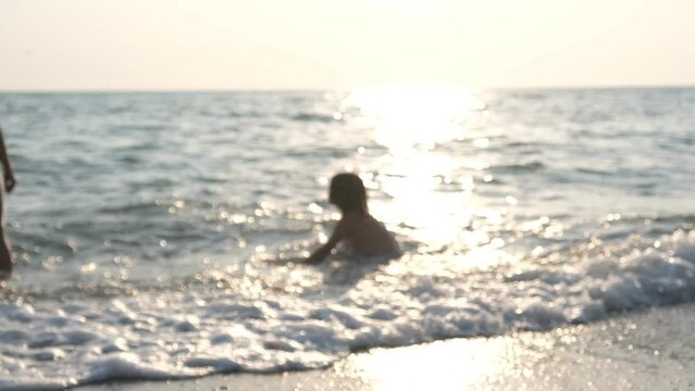 A child playing in the sea at sunset. Video in defocus.