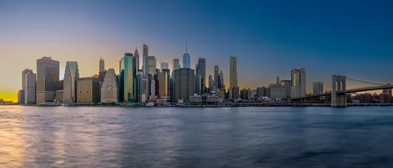 Draagtas Panoramic cityscape about lower Manhattan's skyscrapers.  The photo taken from brooklyn bridge park. Amazing blue hour view and the sundown on the left side, .Old pier's columns on the foreground. © GezaKurkaPhotos