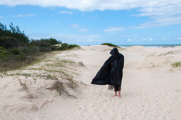 Man in sorcerer costume walking on the dunes of the beach