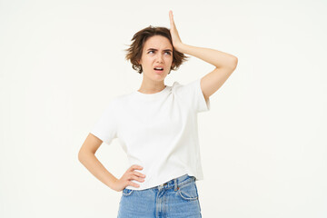 Portrait of woman looking troubled, slap her forehead, standing thoughtful and frowning, facing...