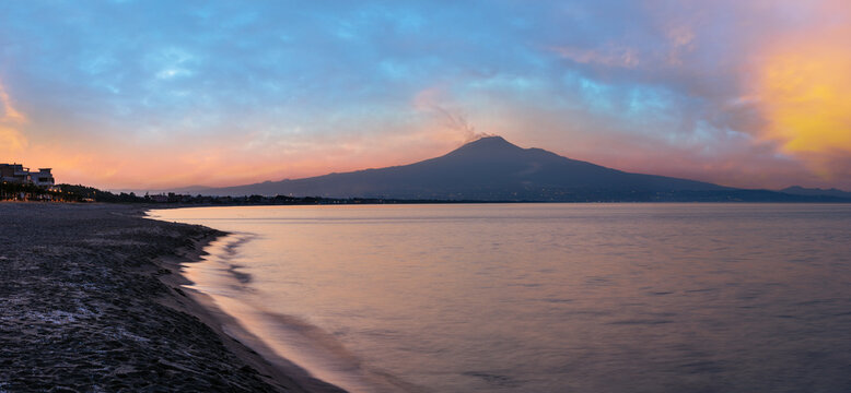 Beautiful sunset twilight on Agnone Bagni sea beach with smoky Etna volcano in far (Siracusa, Sicily, Italy). 