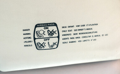 Child seat airbag warning in multiple languages in the car interior, inside the vehicle. Printed on information detail, closeup. Children kids safety during car travel simple abstract concept, nobody