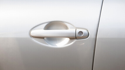 Simple generic silver car door handle with a key lock hole, side front view, object detail, closeup, vehicle doors handle frontal shot. Car safety, security locking the doors abstract concept, nobody