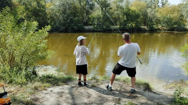 Man, father and his daughter spending good time together, going fishing, resting near river on summer day. Concept of hobby, leisure activity, weekends, family, childhood and parenthood