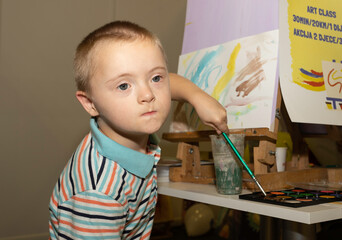 A cute boy with Down Syndrome is having an art class.