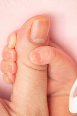 Baby and mother creative minimal concept. The baby is holding the mother's finger on a pastel pink background. Close up, macro shot 