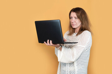 A woman with an alert sad face looks at the laptop screen, reads world business news, thinks about...