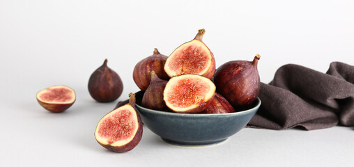 Bowl with fresh ripe figs on light background