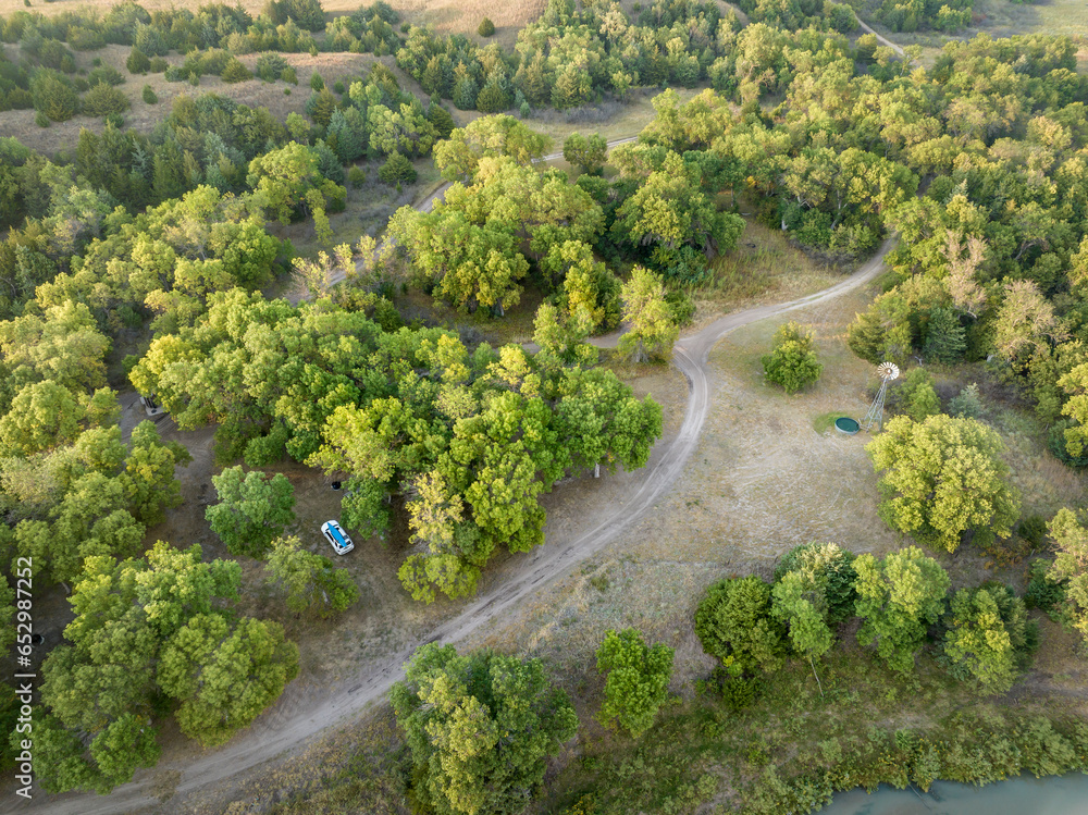 Wall mural Whitetail Campground on the shore of Dismal River in Nebraska National Forest, late summer dawn aerial view with SUV vehicle