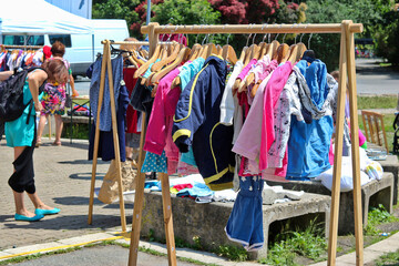 Exchange of used children's clothing in the outdoor area in the park in the city.