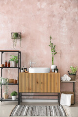 Interior of stylish bathroom with sink, drawers and shelving unit