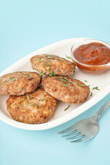 Cutlets with chopped parsley, ketchup and fork on blue background