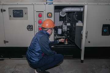 A technician sets up backup power. An engineer in a helmet starts a powerful diesel generator.