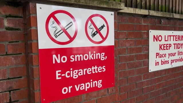 Large wall-mounted public information sign at a UK transport terminus. The sign carries the text ‘No Smoking, E Cigarettes, or Vaping’.