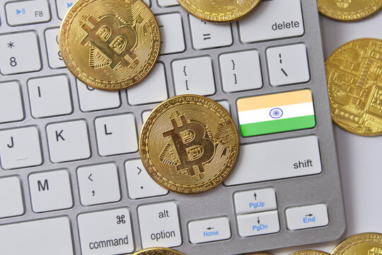 national flag of india on the keyboard with bitcoin coins on a grey background.