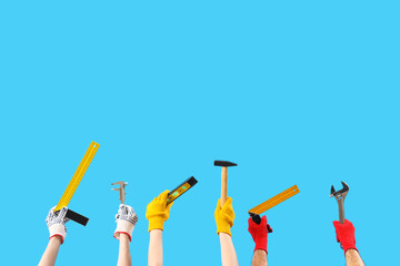 Female and male hands holding different construction tool on blue background