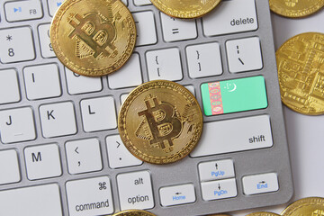 national flag of turkmenistan on the keyboard with bitcoin coins on a grey background.