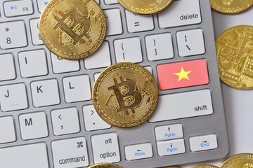 national flag of vietnam on the keyboard with bitcoin coins on a grey background.