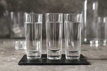 Glasses of vodka on grey background