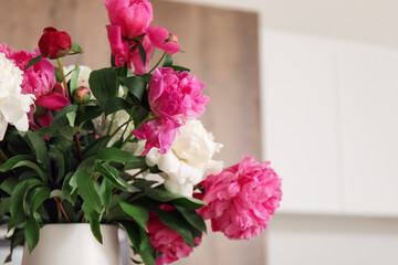 Vase with beautiful peony flowers in modern kitchen, closeup