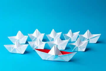 origami paper boat on blue background leadership concept