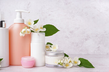Obraz na płótnie Canvas Set of cosmetic products with beautiful jasmine flowers on light background