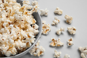 Bowl with tasty popcorn on grey background