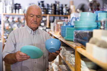 Positive european senior man client consumer choosing variety goods for kitchen at store