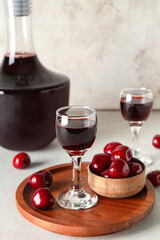 Glasses and bottle with sweet cherry liqueur on white background