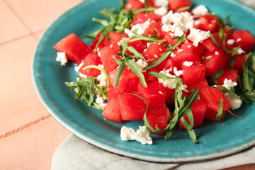 Plate of tasty watermelon salad on beige tile background
