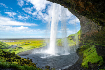 Breathtaking view behind the waterfall at Seljalandsfoss in Iceland on a sunny day